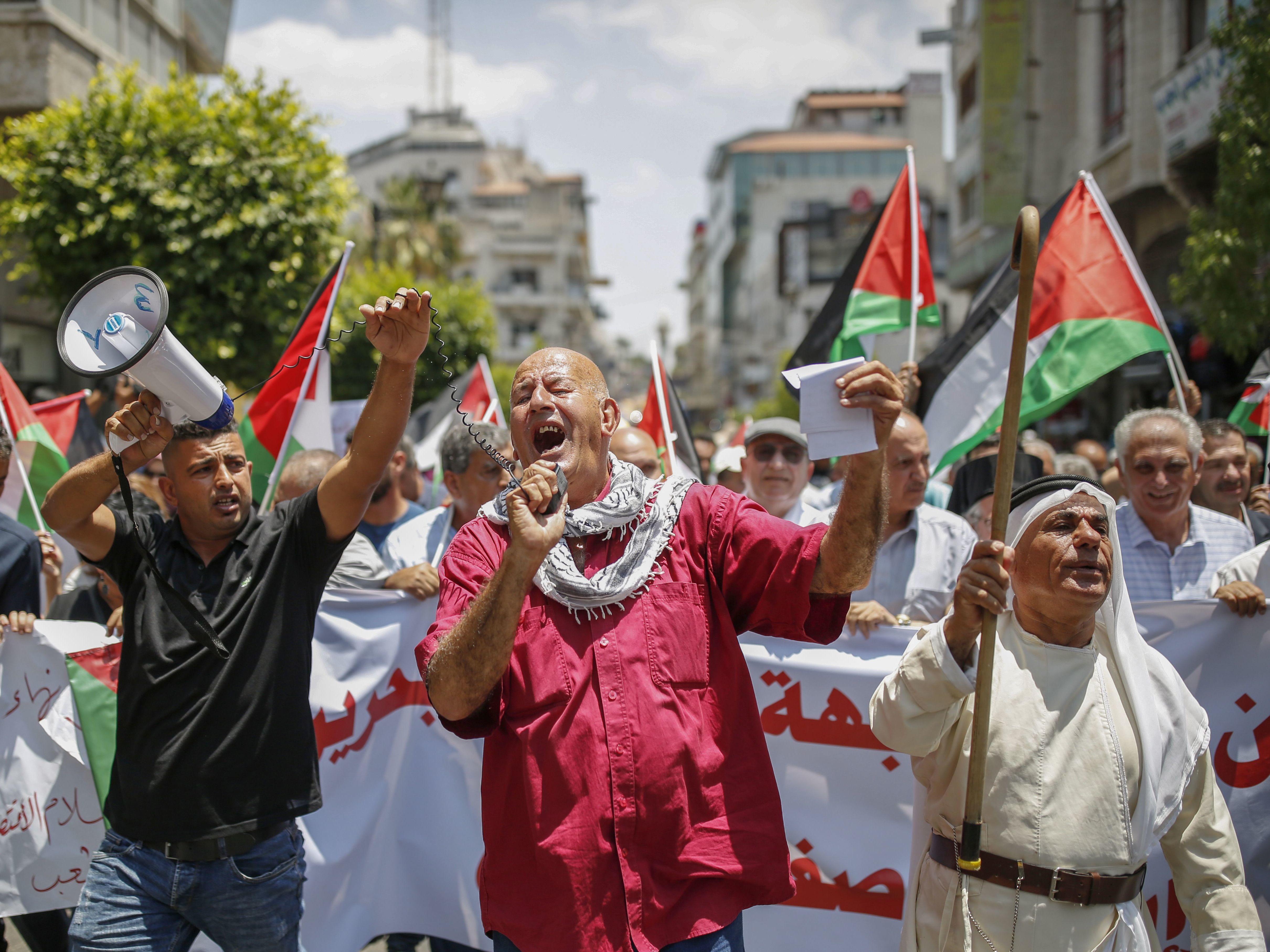 caption: Palestinians in the occupied West Bank town of Ramallah protest the Trump administration's new peace plan on June 15.