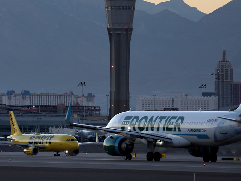 caption: A Frontier Airlines plane (right) prepares to take off from Harry Reid International Airport in Las Vegas, Nevada.