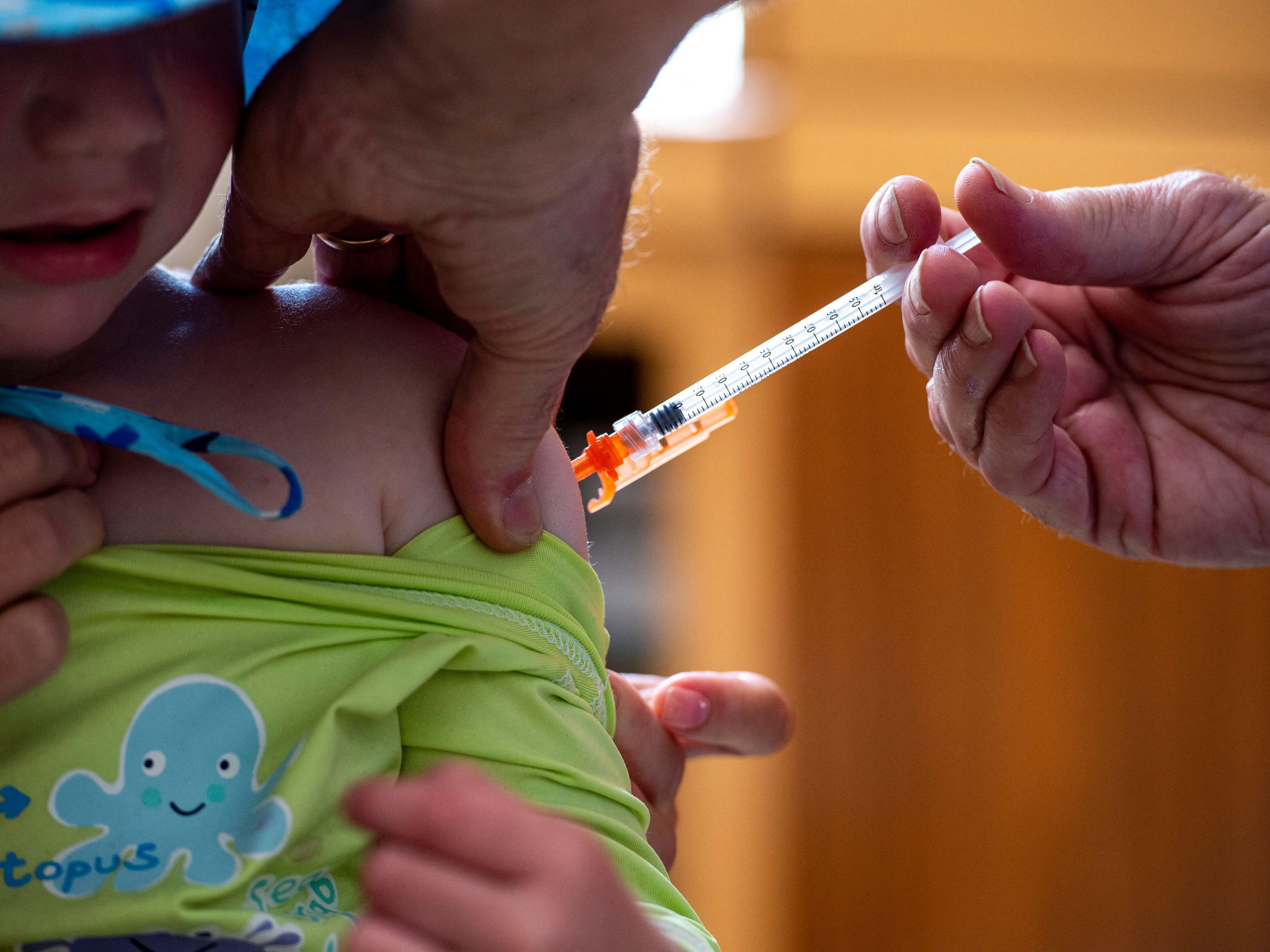 caption: A three year old receives the Covid-19 vaccination on June 21, 2022.