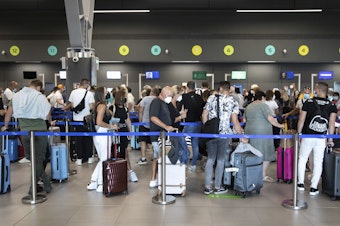 caption: Passengers queue up at Greece's Thessaloniki Makedonia Airport on Sept. 2. Recommendations about physical distancing prove hard to follow at airports — and in the jetway leading to the plane.