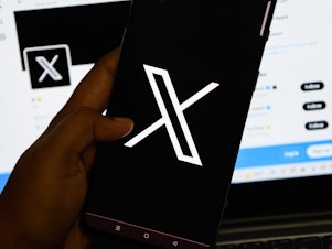 caption: In this photo illustration, the new logo for the social media platform formerly known as Twitter, now X, is seen displayed on a smartphone.