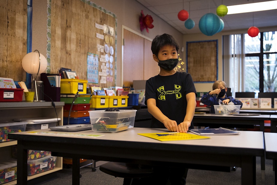 caption: Anthony, a second-grade student at Somerset Elementary School, opens school supplies and folders from his cubby on Thursday, January 21, 2021, as second-grade students returned to in-person learning in Bellevue.