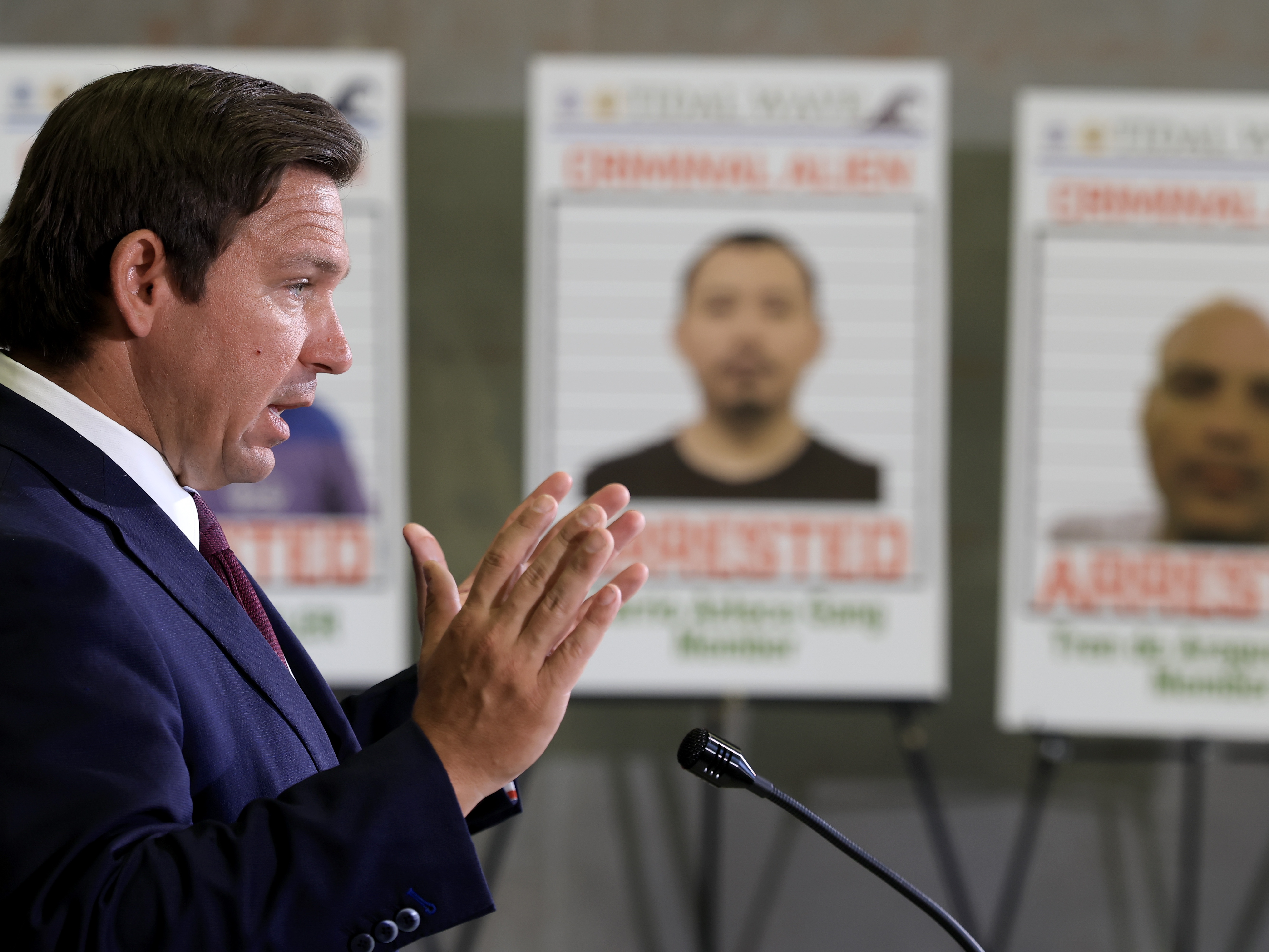caption: Florida Gov. Ron DeSantis speaks during a press conference in front of posters of people that law enforcement arrested, held at the ICE Enforcement and Removal Operations office on May 1, 2025 in Miramar, Fla. Florida has issued its own financial incentives to encourage more local police cooperation with ICE.