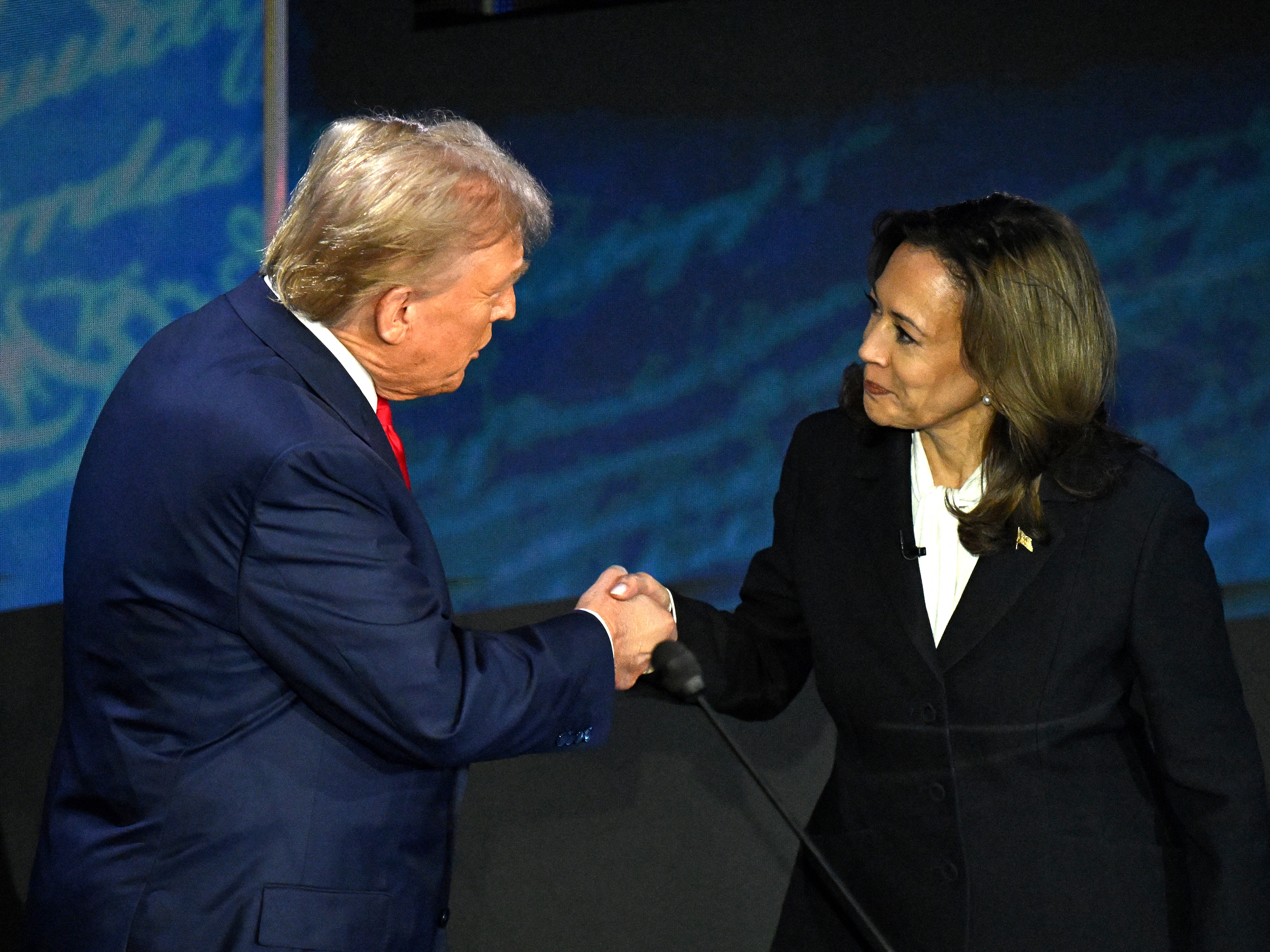 caption: Vice President and Democratic presidential candidate Kamala Harris (R) shakes hands with former president and Republican presidential candidate Donald Trump during the presidential debate in September.