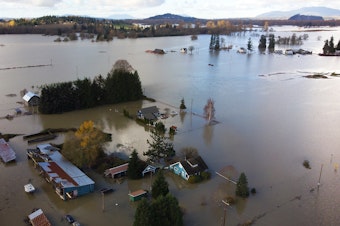 caption: Homes are shown surrounded by flood waters on Tuesday, November 16, 2021, east of Mount Vernon. 