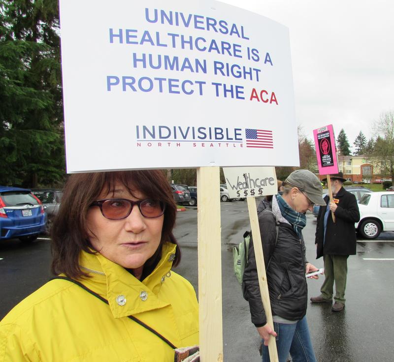 caption: Christine Mathews says she couldn't afford health insurance without the ACA subsidies. She was at a rally last month outside Congresswoman Suzan DelBene’s district office in Bothell.
