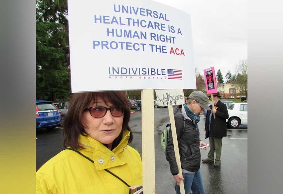 caption: Christine Mathews says she couldn't afford health insurance without the ACA subsidies. She was at a rally last month outside Congresswoman Suzan DelBene’s district office in Bothell.
