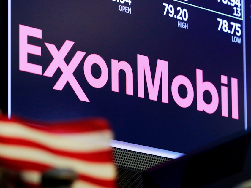 caption: The logo for ExxonMobil above a trading post on the floor of the New York Stock Exchange. The company has apologized after one of its lobbyists talked about undermining climate action in an undercover video.