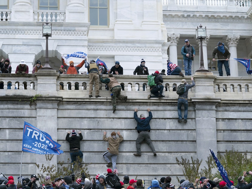 caption: Insurrectionists loyal to President Donald Trump scale the west wall of the the U.S. Capitol on Jan. 6, 2021.