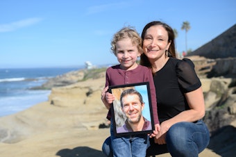 caption: Laura Keenan and her son, Evan, hold a photo of her late husband Matt Keenan, who was killed while riding his bike in San Diego in 2021.