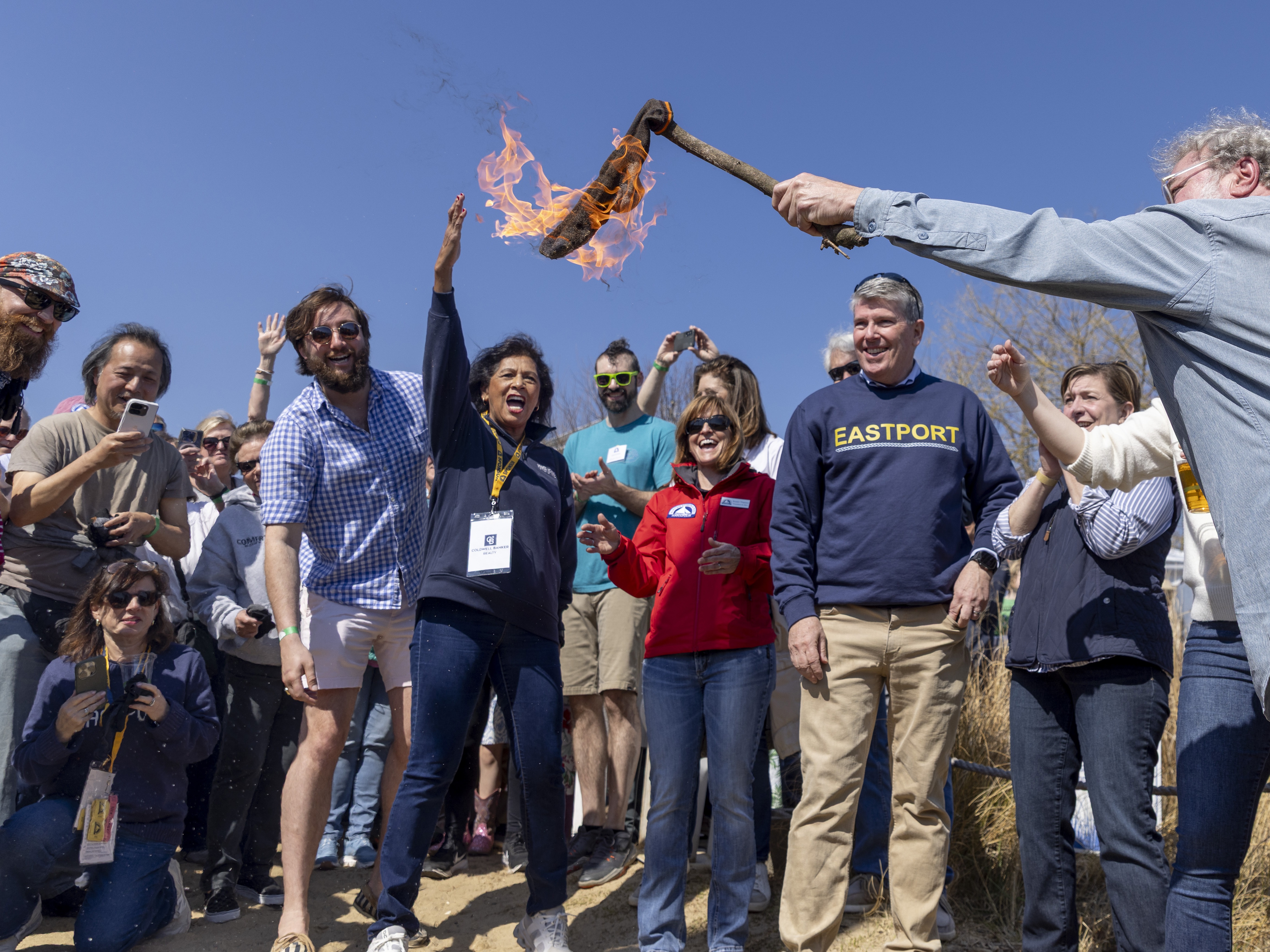 caption: After reciting his "Ode to the Equinox," Annapolis poet laureate Jefferson Holland, right, holds his burning sock high as the crowd cheers to kick off the sock-burning tradition at the Annapolis Maritime Museum &amp; Park on Saturday.