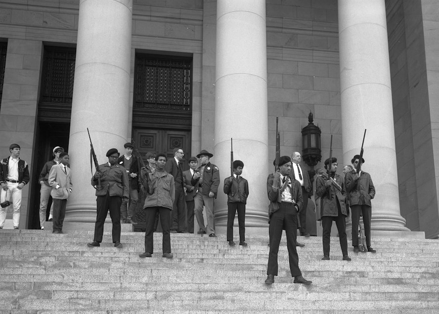 caption: Elmer Dixon and other Seattle Black Panthers gather on the steps of the Capitol in Olympia on February 28, 1969, to protest a bill aiming to it a crime to exhibit firearms with 'an intent to intimidate others.'