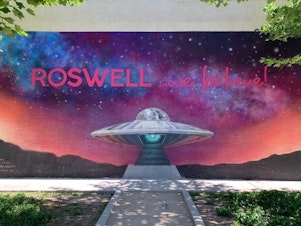 caption: A mural in Roswell, N.M., displays the town slogan. A mysterious aircraft crash in 1947 led to the local legend of visitors from another planet.