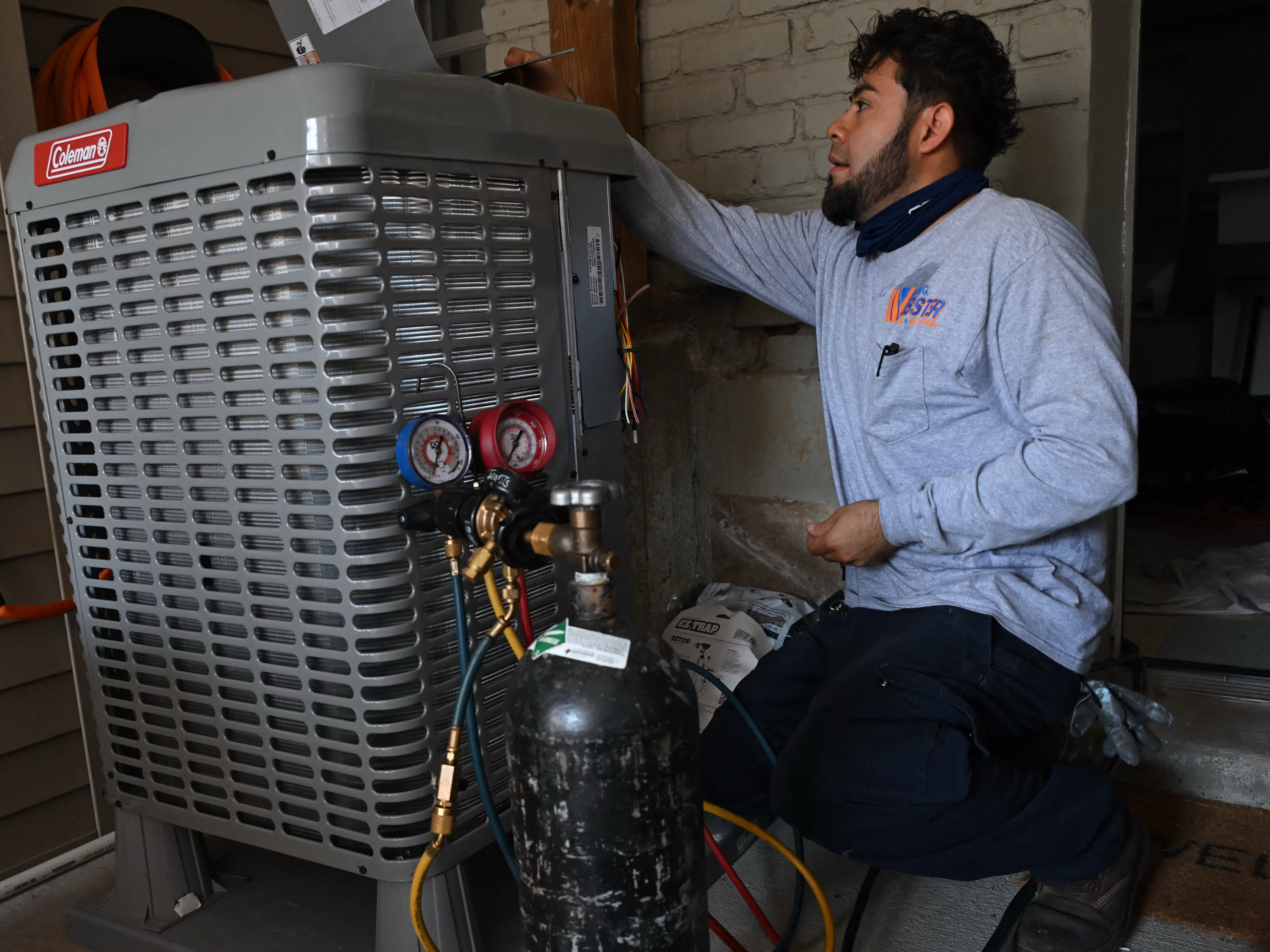 caption: A technician installs an electrical heat pump at a home in Washington, DC, in August 2024.