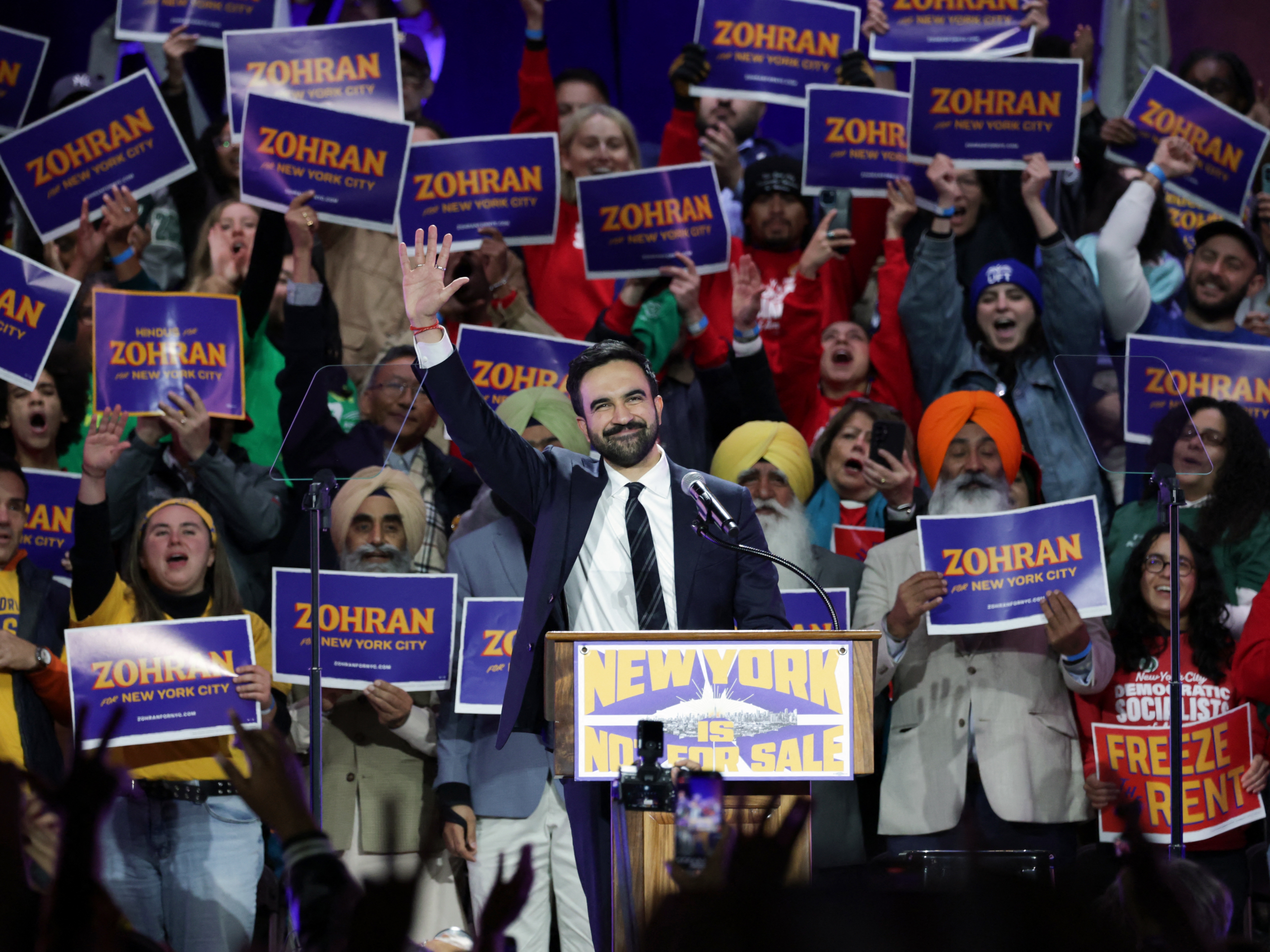 caption: New York City mayoral candidate Zohran Mamdani waves during a campaign rally at Forest Hills Stadium in New York City.