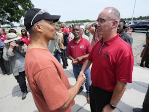 caption: Autoworker Kevin Winston, left, talks with United Auto Workers president Shawn Fain outside the General Motors Factory Zero plant in Hamtramck, Mich., on July 12.