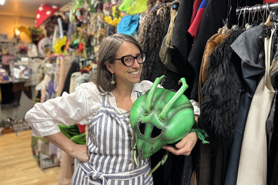 caption: Kyra Stewart poses with a leather praying mantis head. Behind her is a brown shawl made of Icelandic Sheep's Fleece.