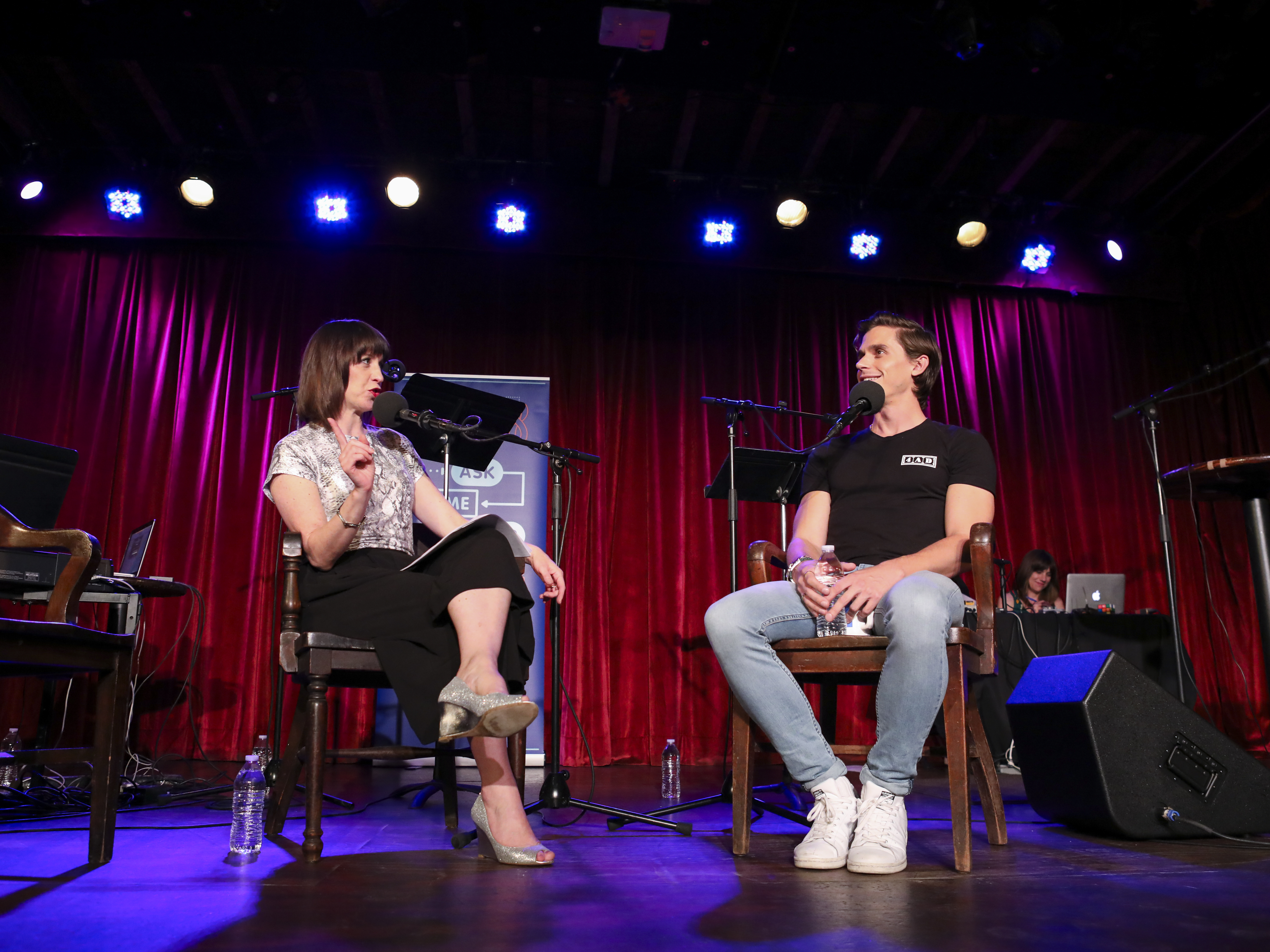 caption: <em>Ask Me Another</em> host Ophira Eisenberg chats with Antoni Porowski at the Bell House in Brooklyn, New York.