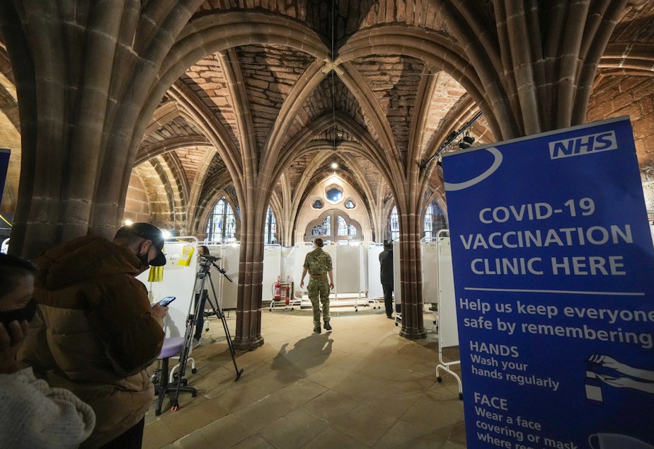 caption: The fast spread of omicron has led many wealthy countries to speed up vaccine rollout and widen booster programs. Here, British soldiers administer shots at a vaccine clinic at Chester Cathedral in Manchester, England, Wednesday.