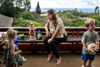 caption: Arica Lynn Souza and her children Ayla, 3, left, and Silas, 4, on the porch of the family home where they are staying temporarily after losing their Lahaina townhome in the wildfires.