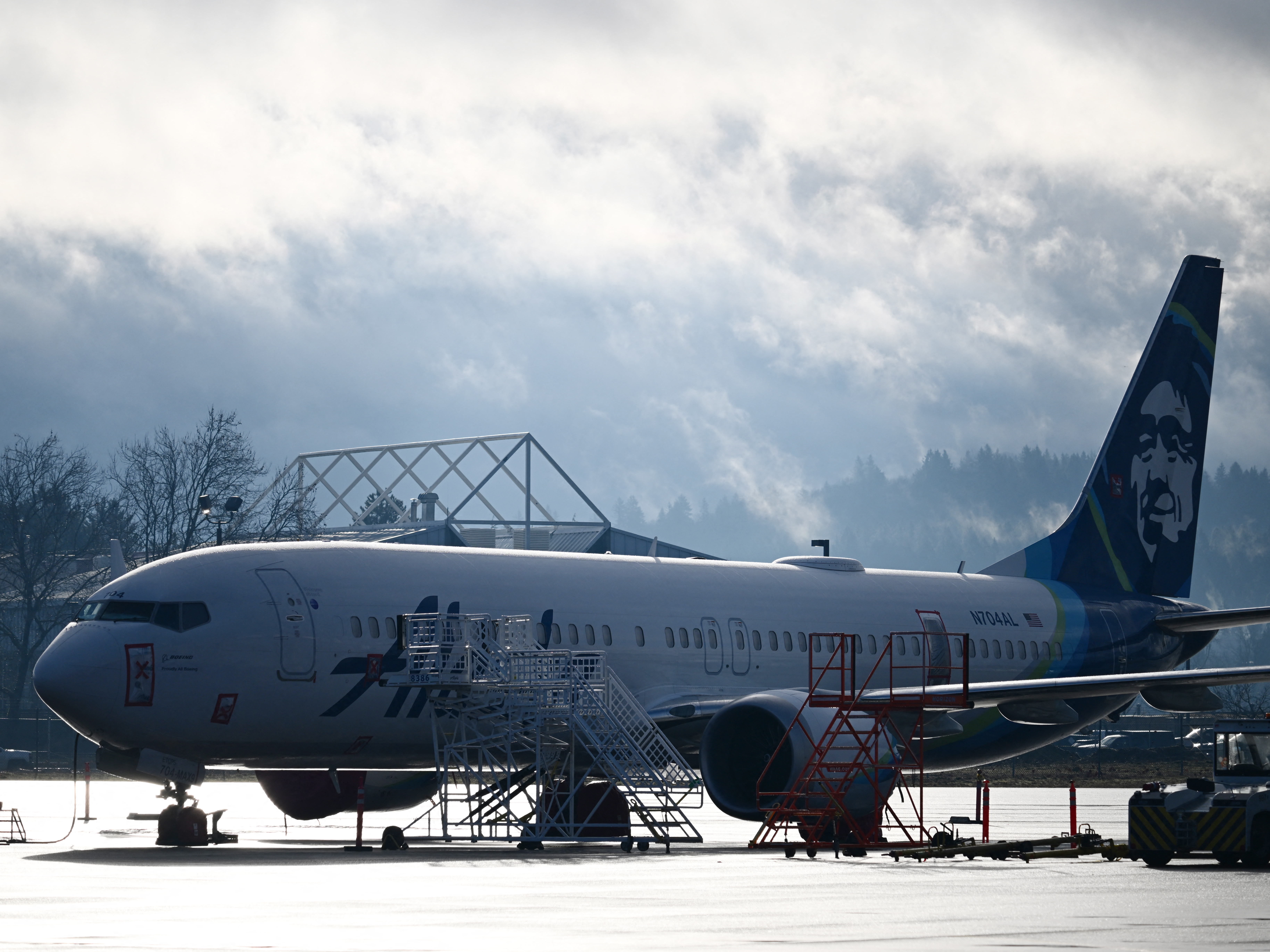 caption: Alaska Airlines N704AL, a 737 Max 9, which made an emergency landing at Portland International Airport on January 5 is parked at a maintenance hanger in Portland, Ore. on January 23, 2024. One of two door plugs on the emergency exit door blew out shortly after the plane took off from Portland.