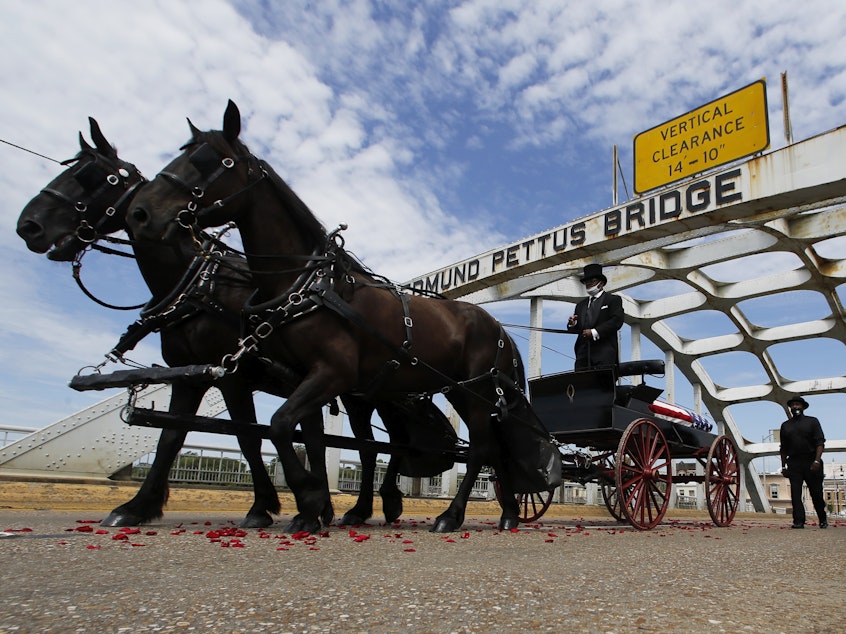 caption: The casket of Rep. John Lewis crosses the Edmund Pettus Bridge by horse-drawn carriage during a memorial service for Lewis on July 26 in Selma, Ala.
