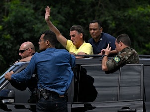 caption: Brazilian President Jair Bolsonaro waves at supporters after voting in the presidential runoff election, on his way to Galeao airport in Rio de Janeiro on Sunday.