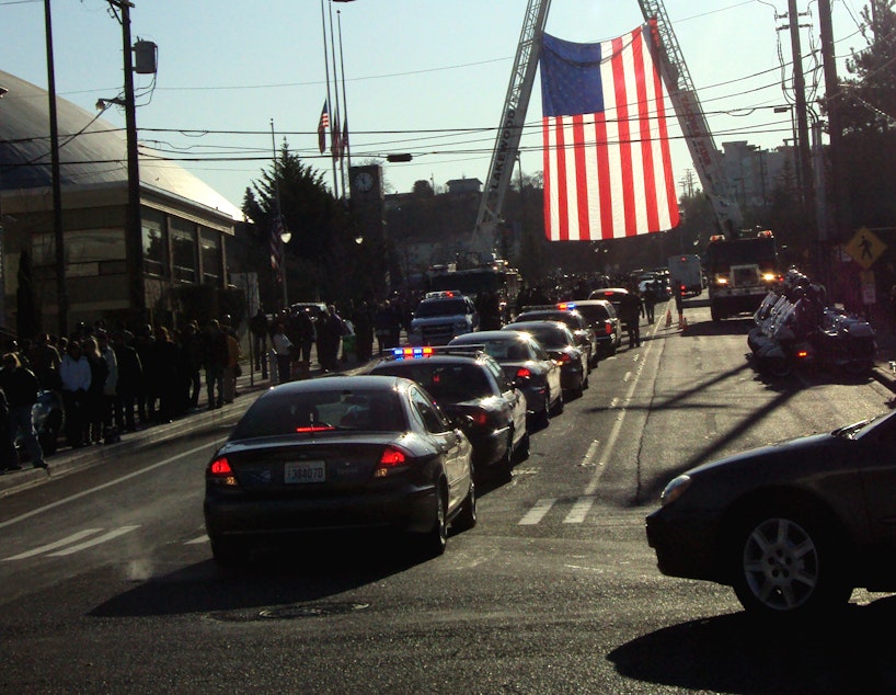 caption: Police cars proceed through Tacoma during a memorial on Dec. 8, 2009 to four Lakewood officers who were shot to death.