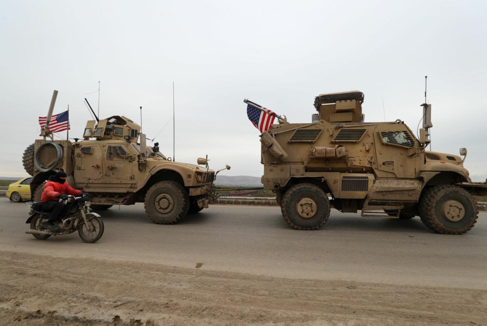 caption: A US military convoy drives on the outskirts of the Kurdish-controlled northern Syrian city of Qamishli on February 12, 2020. (Delil Souleiman/AFP) 