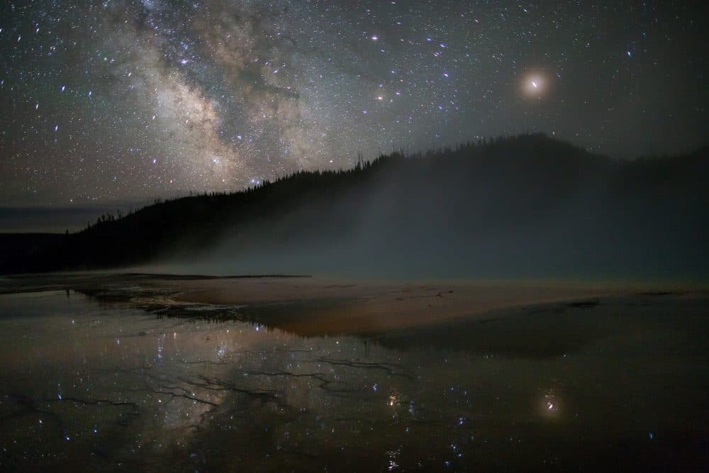 caption: The Milky Way above Grand Prismatic Spring in Yellowstone National Park in Wyoming in July 2016. The spring was the same location where Here & Now's Peter O'Dowd observed the park's night skies earlier this week. (Neal Herbert/National Park Service via Flickr)