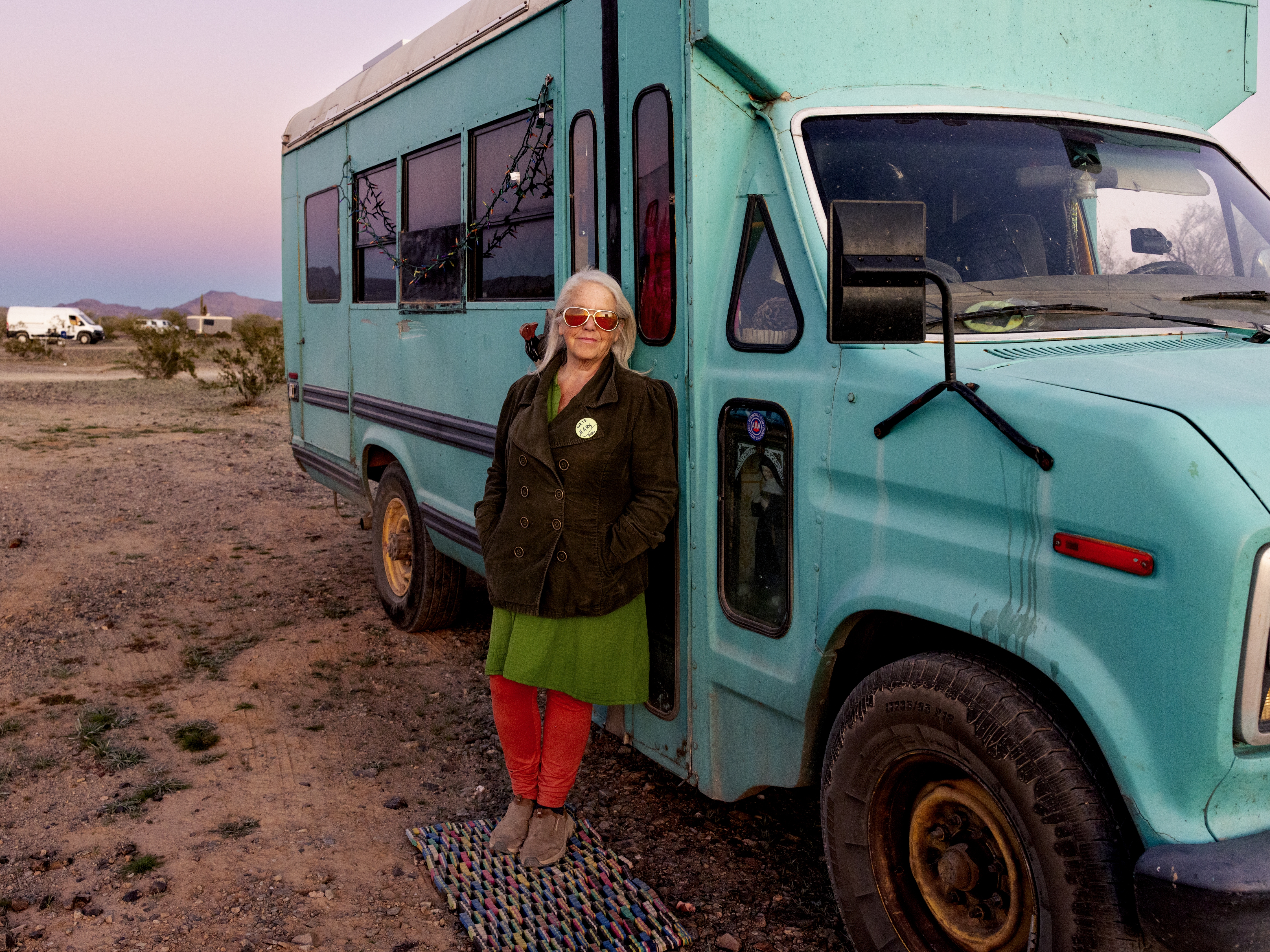 caption: Mary Freuer stands outside of her teal converted school bus, also known as a skoolie.