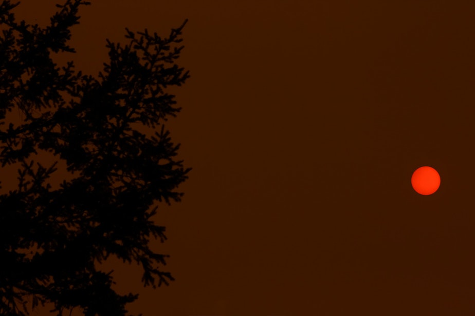 caption: Smoky skies from wildfires in Vancouver makes for an orange sun as it sets.