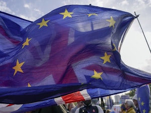 caption: A Union flag waves behind a European Union flag outside the Houses of Parliament in London on Oct. 19. The British government denied a report on Nov. 20 that it is seeking a "Swiss-style" relationship with the European Union that would remove many of the economic barriers erected by Brexit — even as it tries to repair ties with the bloc after years of acrimony.