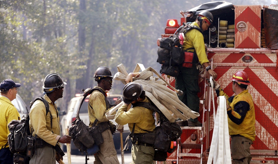 caption: Firefighters line up to get gear out of the back of a fire truck as they get ready to head for a fire Thursday, Aug. 20, 2015, in Twisp, Wash.