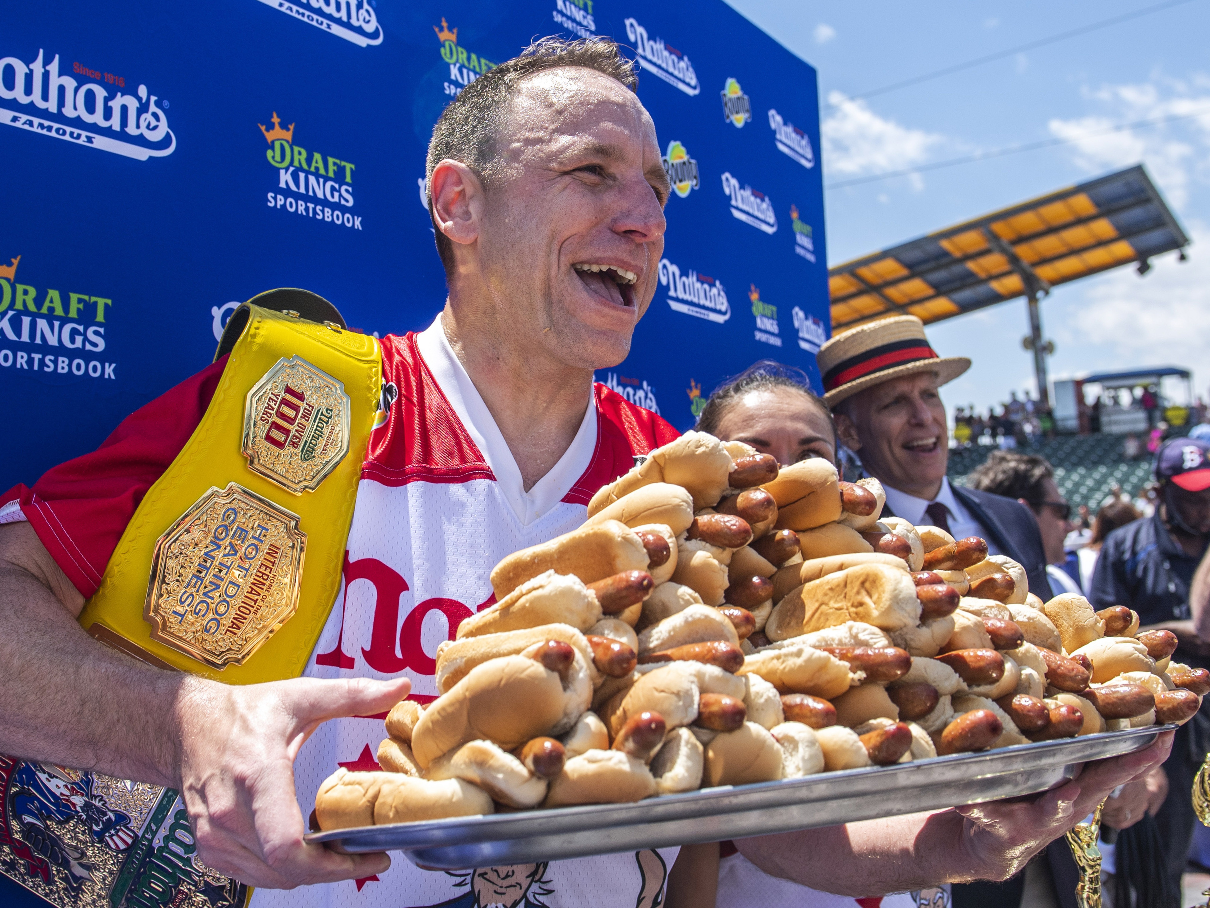 caption: Sixteen-time champion Joey Chestnut poses after his 2021 Nathan's Famous Fourth of July International Hot Dog-Eating Contest victory on Coney Island. He returns to the stage this summer after being banned last year.