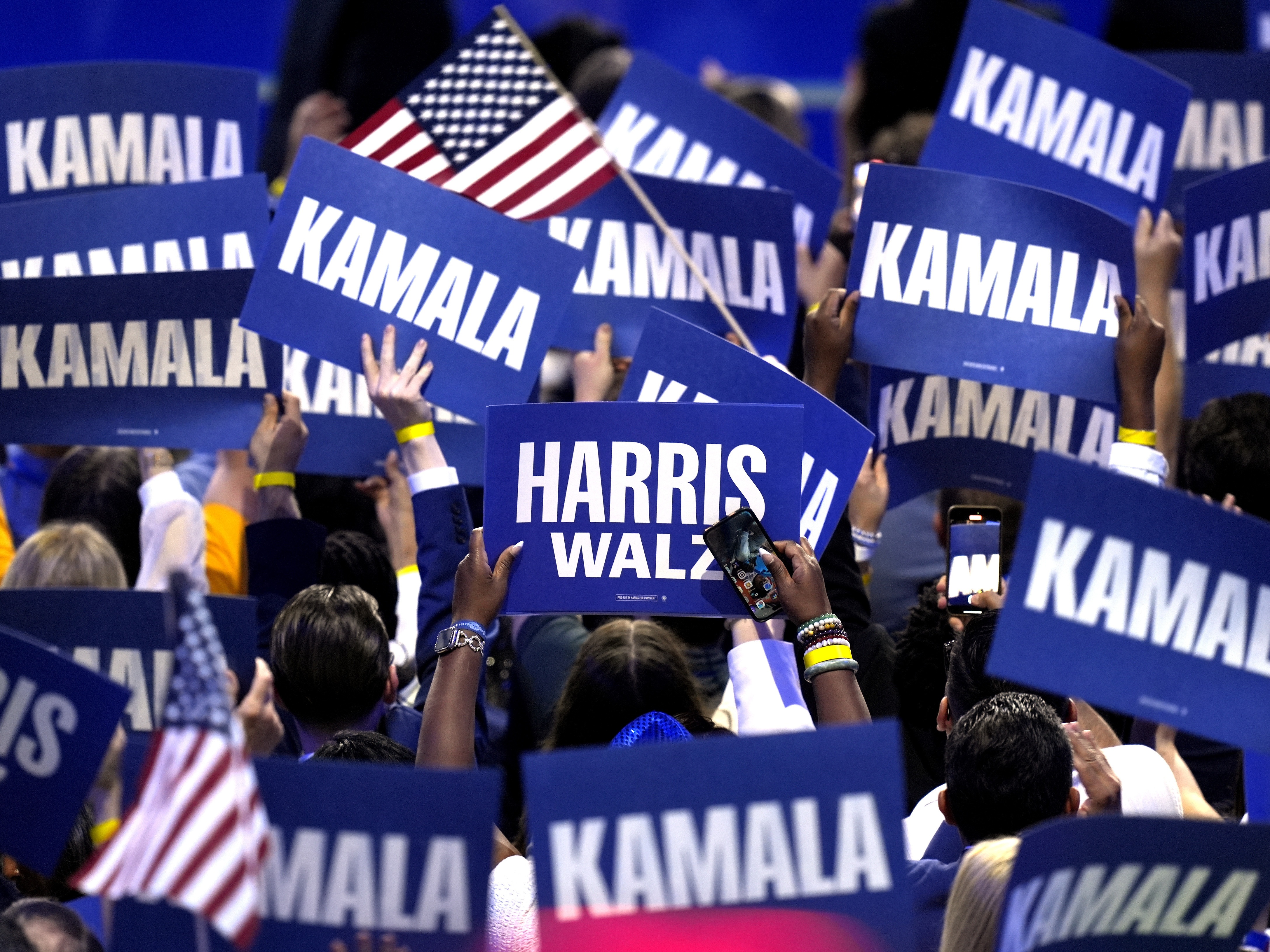 caption: Supporters carry signs as Democratic presidential nominee Vice President Kamala Harris speaks during the Democratic National Convention on Aug. 22 in Chicago.