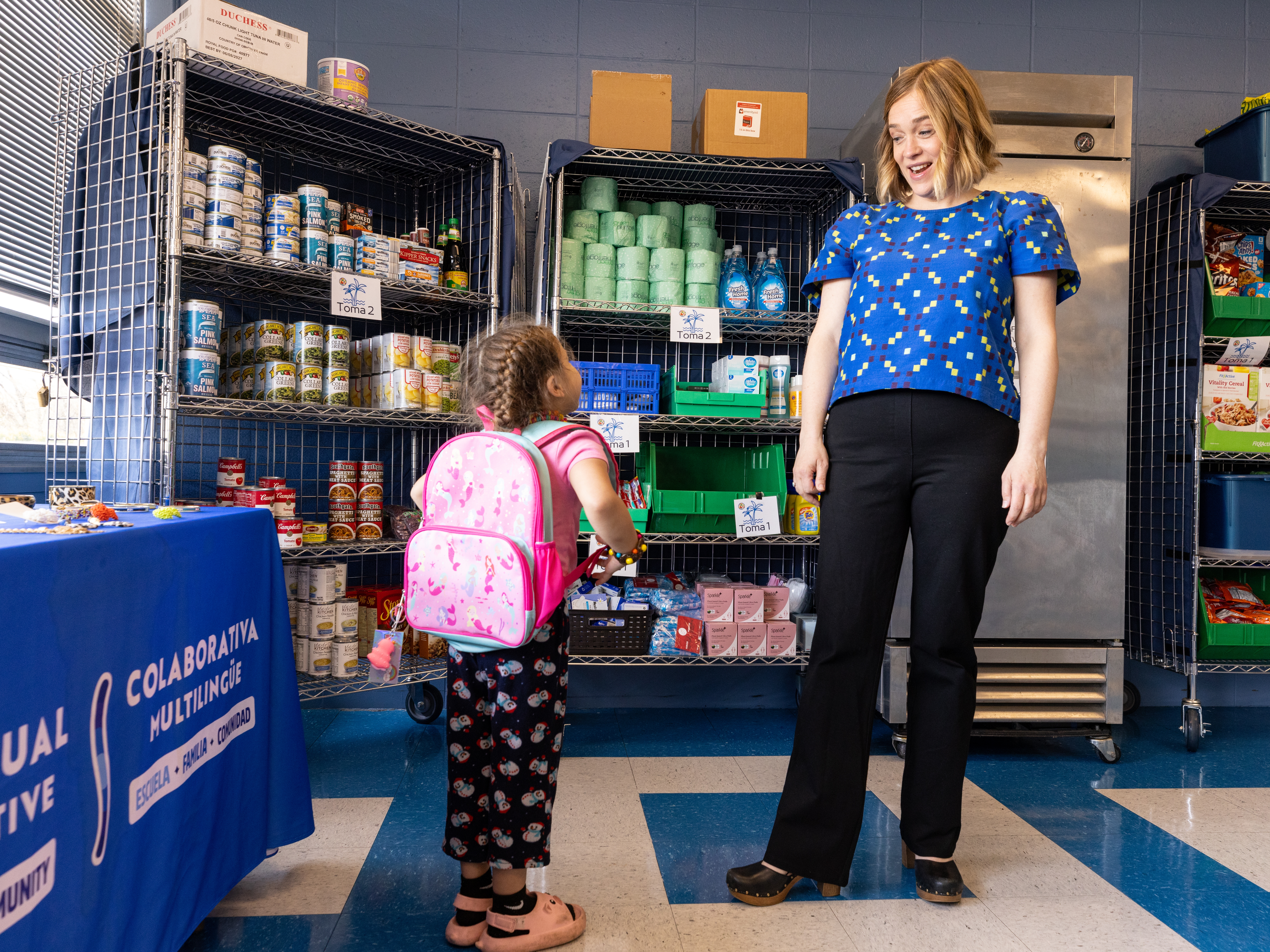 caption: Megan Mainzer, the McKinney-Vento liaison for Middletown Public Schools in Rhode Island, speaks with a young girl at the Island Oasis, a food and clothing pantry that's managed, in part, with federal grant money.