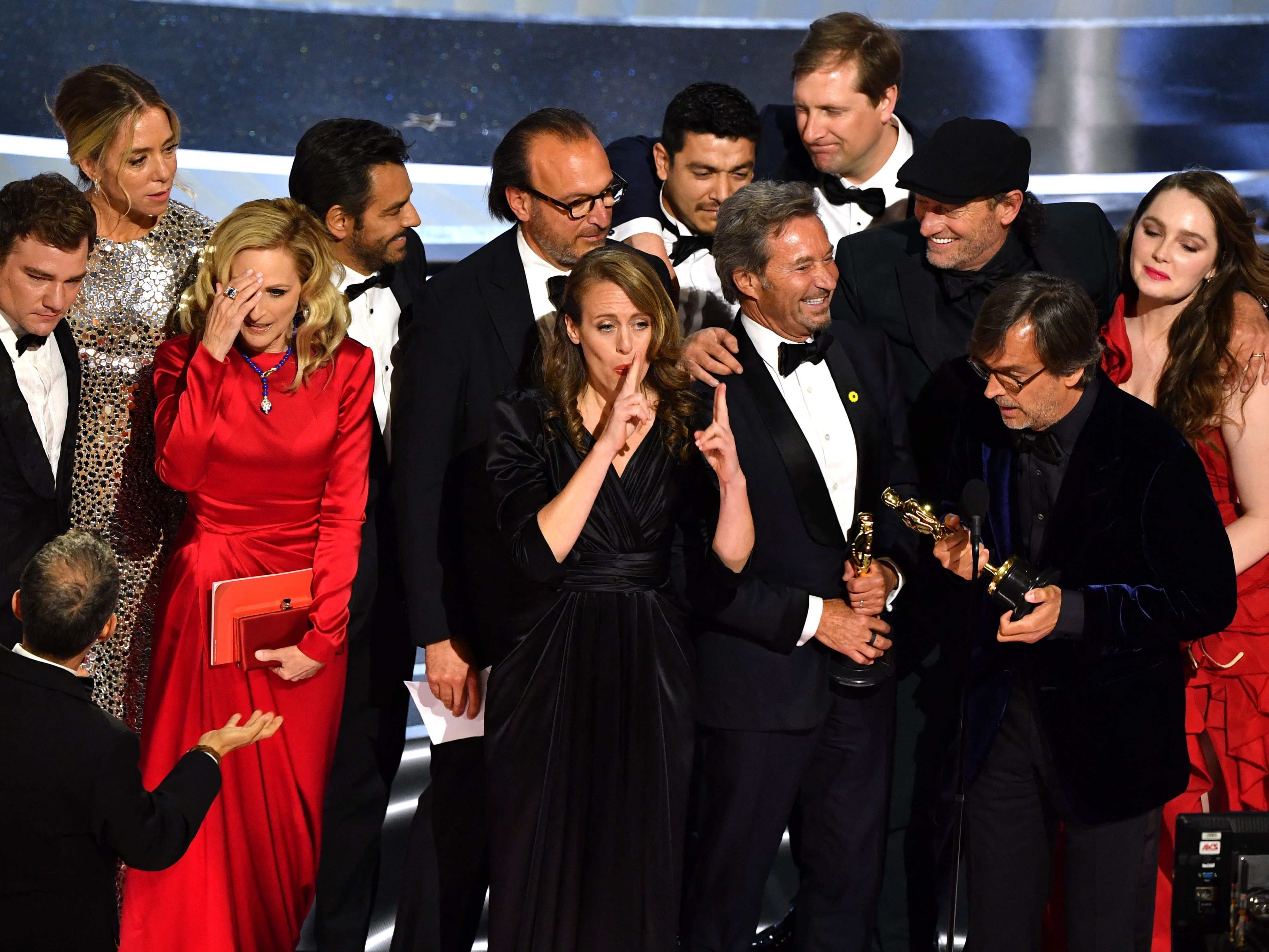 caption: The cast and crew of CODA accept their award onstage.