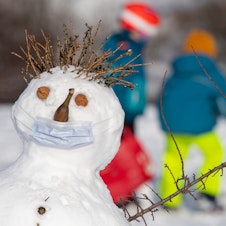 caption: 07 January 2021, Bavaria, Munich: The snowman "Claude", who was built on a hill in the Olympic complex, wears a mouth-nose protection over his nose, which is made of a banana.