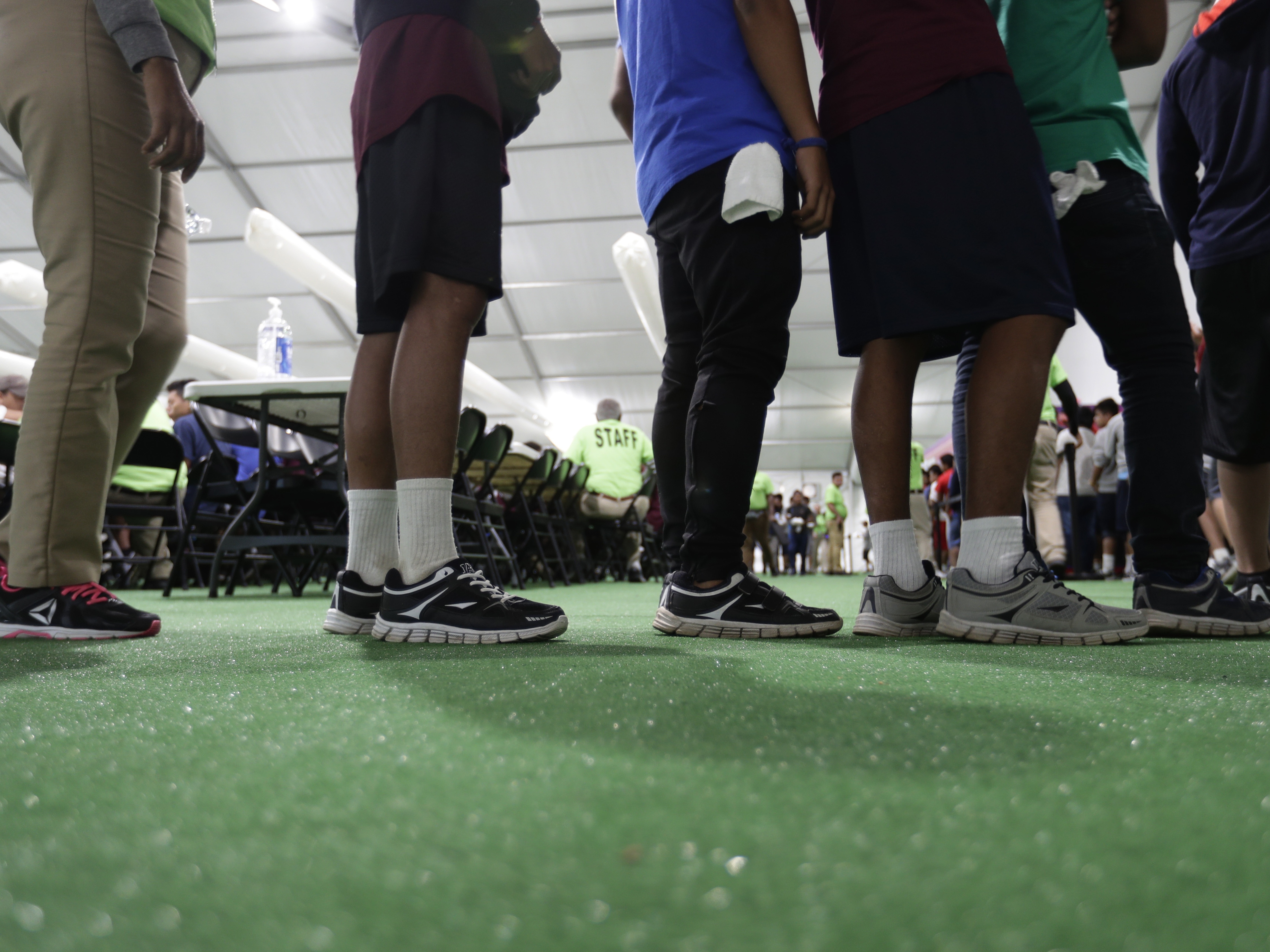 caption: Immigrants line up in the dining hall at a U.S. government holding center for migrant children, July 9, 2019, in Carrizo Springs, Texas.
