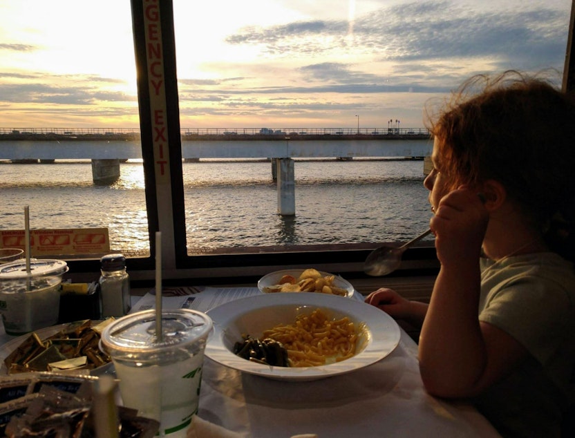 caption: Transportation analyst Seth Kaplan's daughter enjoys macaroni and cheese with a view while riding in an Amtrak dining car. (Photo by Seth Kaplan/Here & Now)