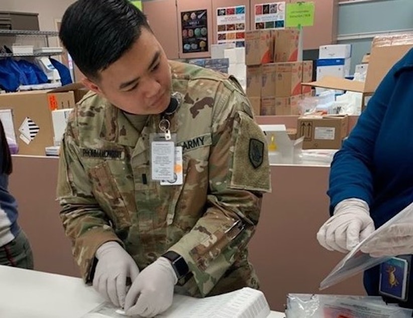 caption: A Washington Army National Guard soldier consults instructions while assembling a Covid-19 test kit at a state warehouse in Tumwater. The National Guard is currently helping to assemble 30,000 kits for distribution to local public health agencies. 