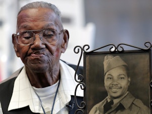 caption: World War II veteran Lawrence Brooks, pictured holding a photo of himself as a soldier in 1943, died on Wednesday at age 112.