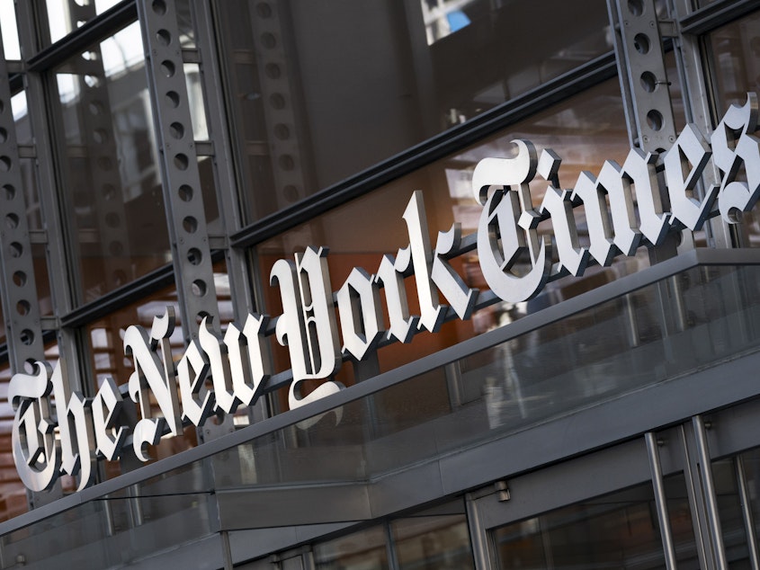 caption: A sign for The New York Times hangs above the entrance to its building on May 6, 2021 in New York.