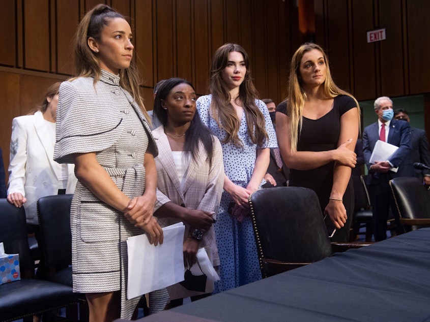 caption: U.S. Olympic gymnasts Aly Raisman, Simone Biles, McKayla Maroney and gymnast Maggie Nichols appear at a Senate Judiciary hearing on September 15, 2021, regarding the Inspector General's report about the FBI's handling of abuse claims against former doctor Larry Nassar.
