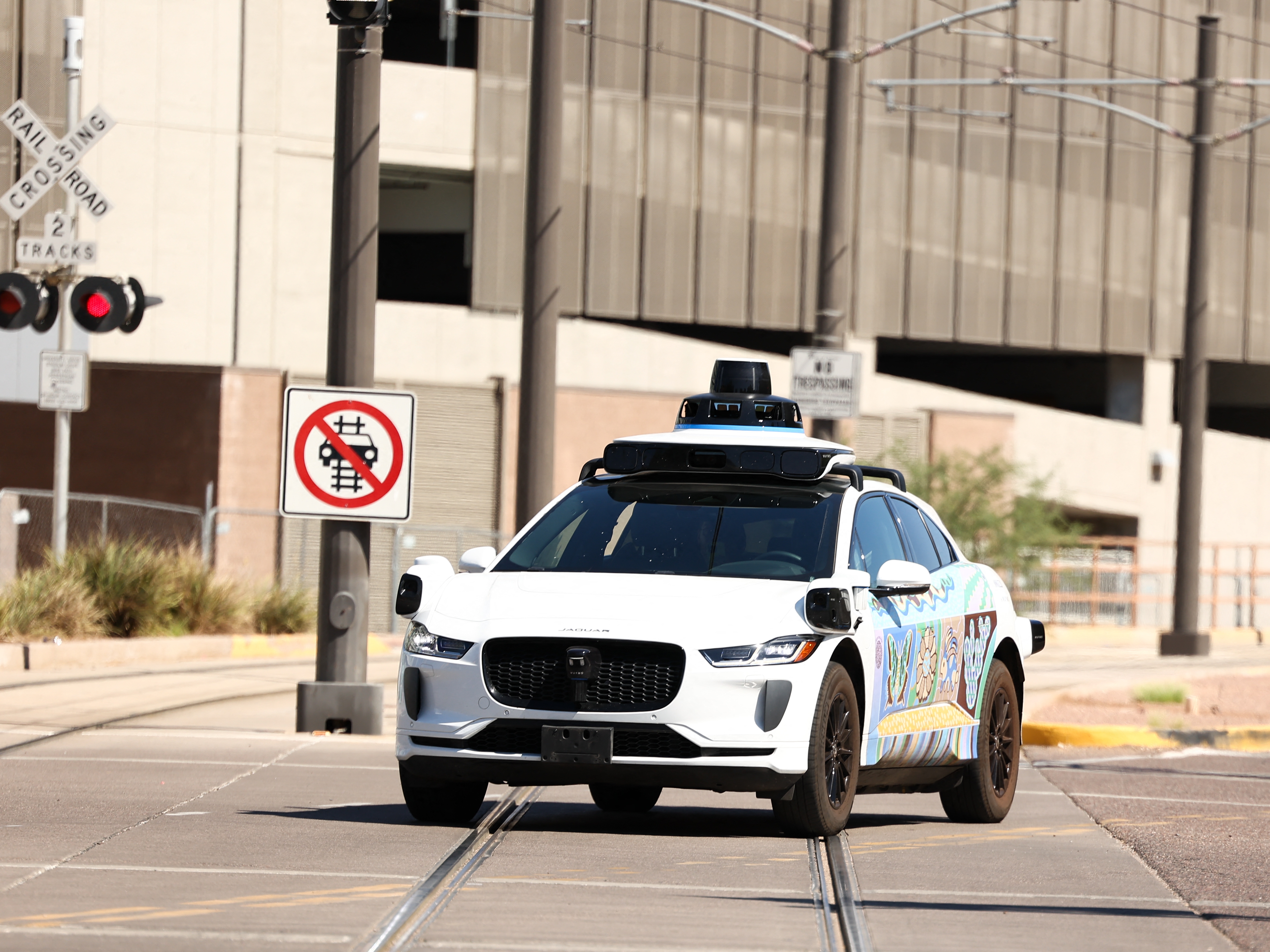 caption: A Waymo autonomous Jaguar electric vehicle is seen in Tempe, Ariz., on the outskirts of Phoenix, on Sept. 15. The company is recalling software for its robotaxis after reports that some of them failed to stop for school buses.