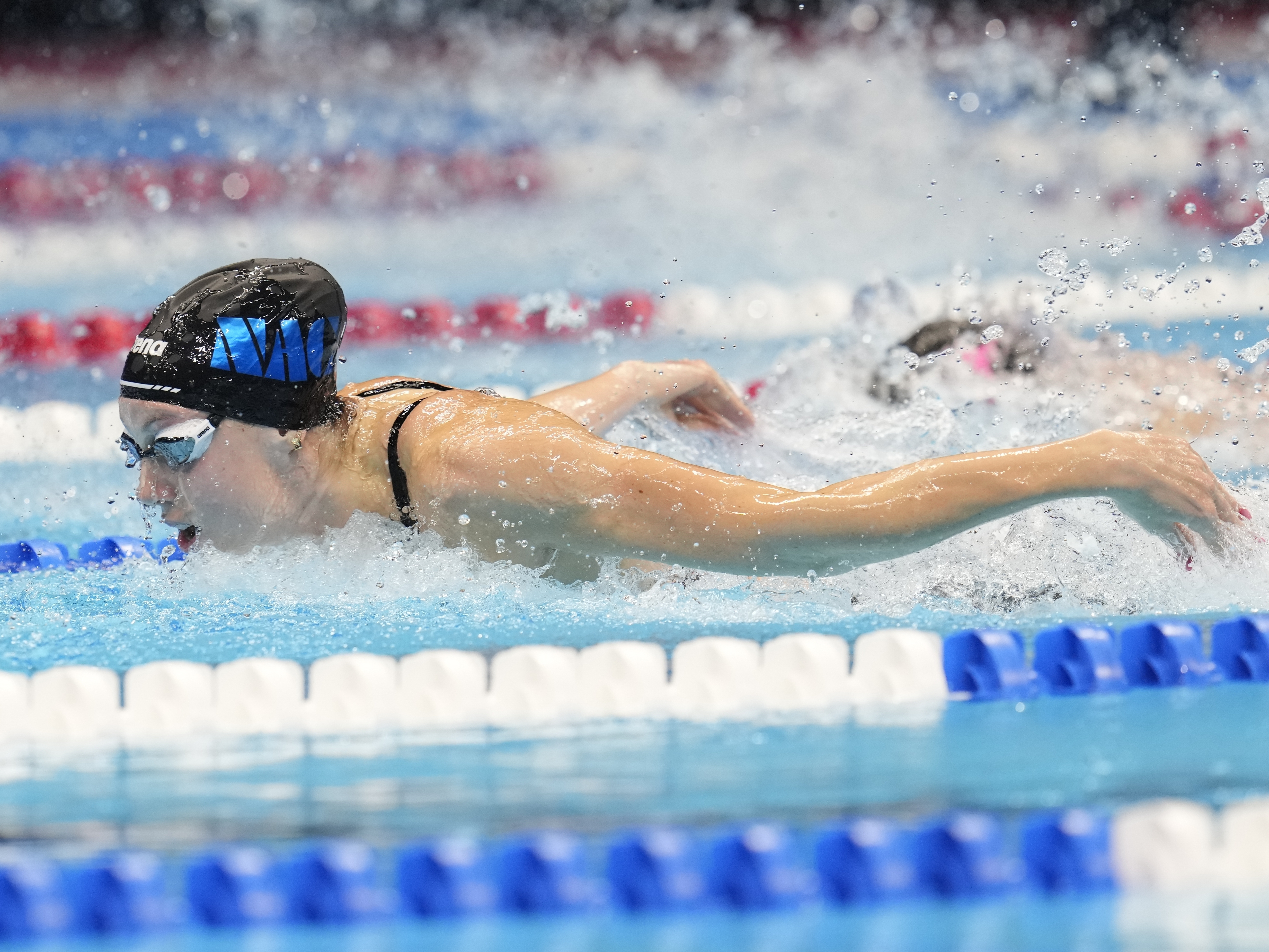 caption: Gretchen Walsh swims during the Women's 100 butterfly finals on Sunday at the U.S. Swimming Olympic Trials in Indianapolis.