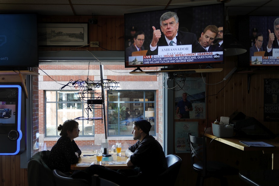 caption: Olivia Tobin and her fiancé, Jordan Ashby, ignore the televised impeachment hearings playing on monitors at the Commercial Street Pub, Wednesday, Nov. 13, 2019, in Portland, Maine. (Robert F. Bukaty/AP)