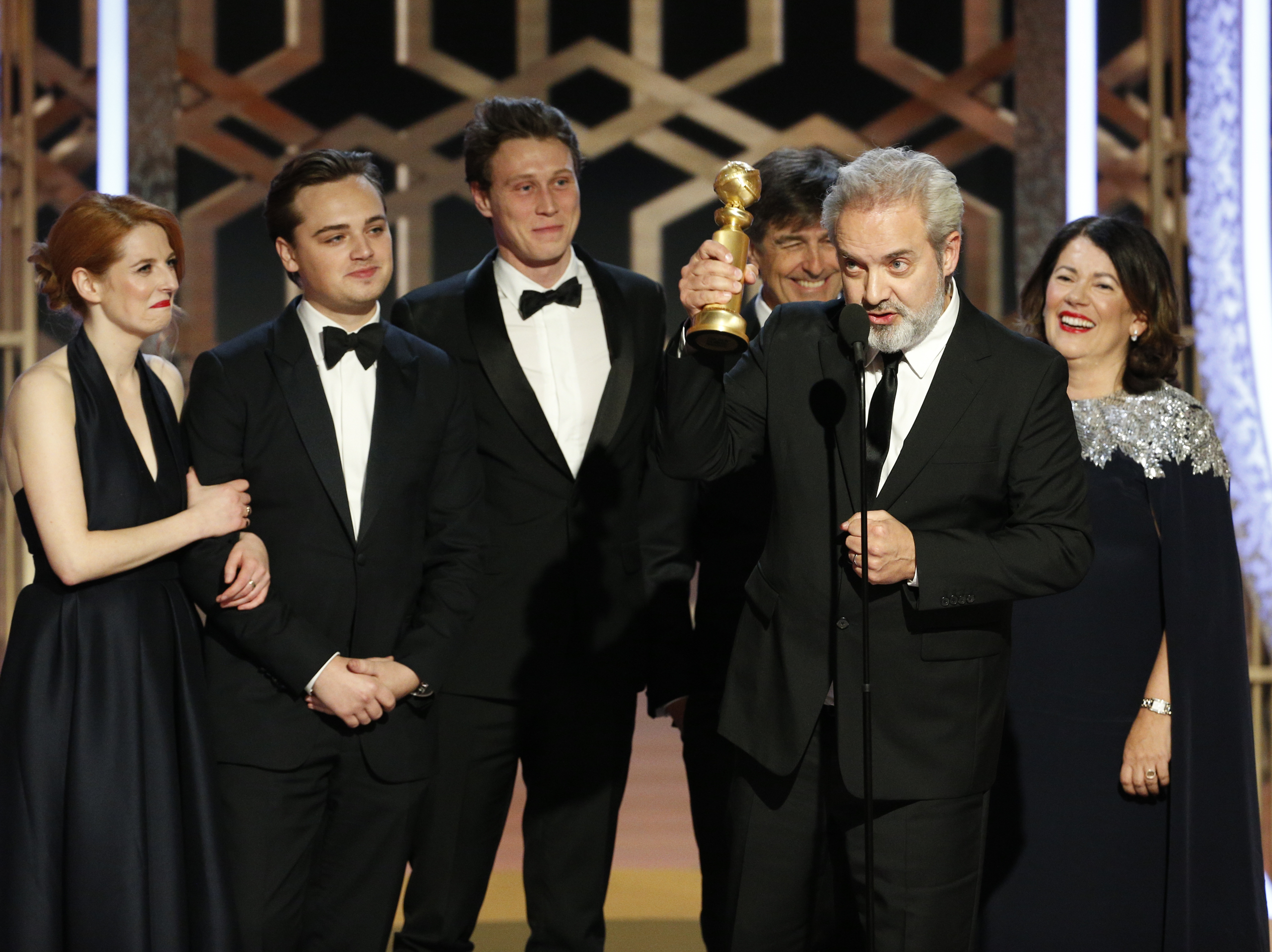 caption: Sam Mendes accepts the award for best drama movie for <em>1917</em> at the Golden Globes on Sunday night.
