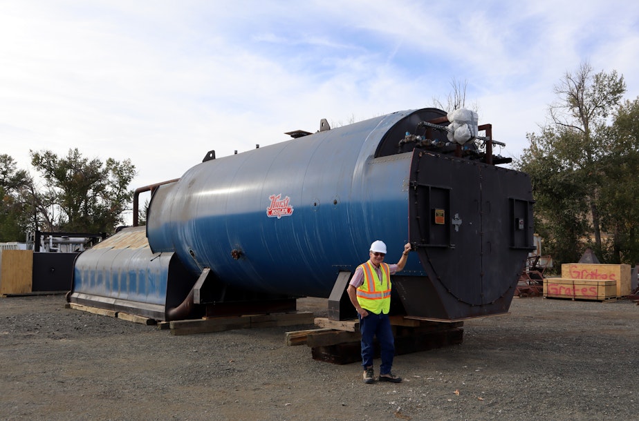 caption: Biomass Operations Specialist John Rowell stands next to a boiler that awaits installation pending permits.